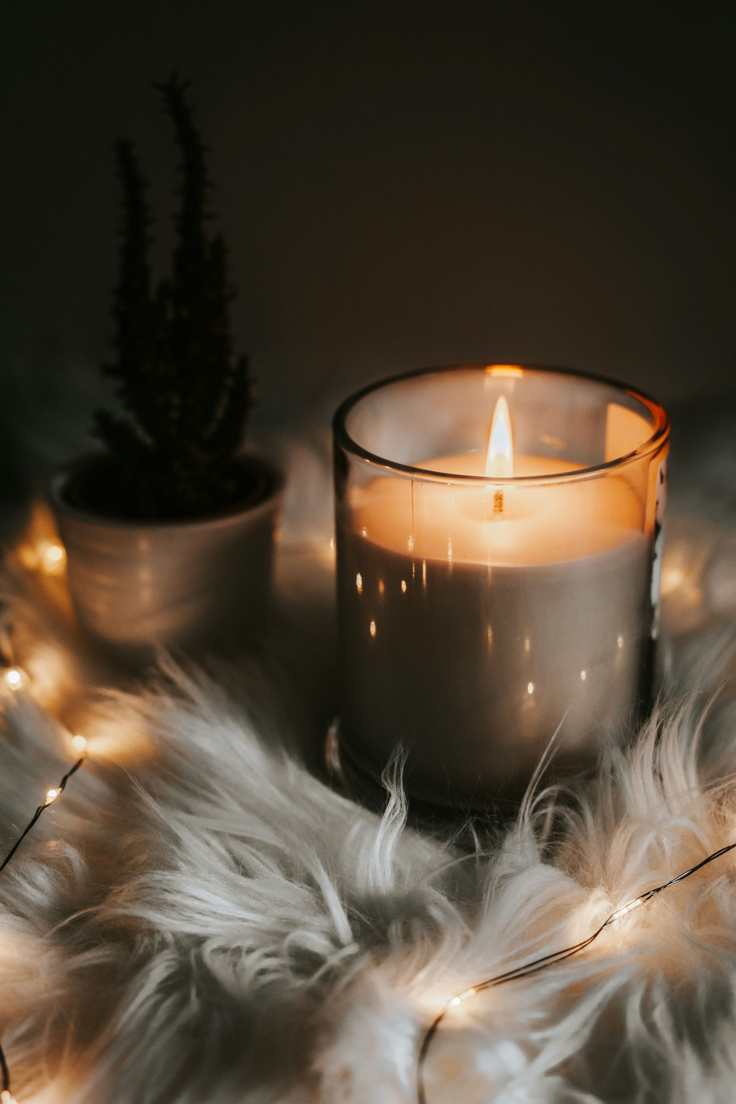 A glowing Lumick candle in a warm cream and wood setting